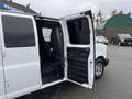 A white 2012 Chevrolet Express van with open side doors revealing a gray interior and seating