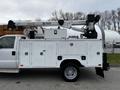 A 2016 Ford F-550 work truck with a white exterior and a mounted crane on top featuring an extended boom and various compartments on the side for tools and equipment