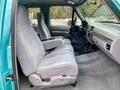 Interior view of a 1995 Ford F-150 XLT SuperCab featuring light gray cloth seats and a center console surrounded by a clean cabin design