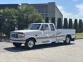 A white 1995 Ford F-250 pickup truck with a sleek design custom graphics on the side and chrome wheels parked on a paved surface