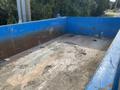 A 2002 Ford F-550 with a blue dump bed showing dirt and debris in the container