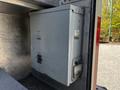 A gray metal storage compartment on a 2006 Emergency One Fire Truck with a latch and a small control panel