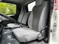 Interior view of a 2018 Isuzu NPR showing the driver's seat and passenger seats with gray fabric upholstery and a simple dashboard design