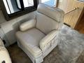 A light beige leather recliner chair with wide armrests and soft cushions