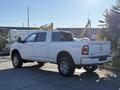 A 2023 RAM 3500 pickup truck in white with a crew cab and chrome wheels parked on a pavement