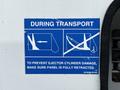 A blue warning sign instructing to ensure the panel is fully retracted during transport to prevent damage to the ejector cylinder