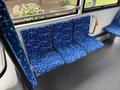 Three blue bus seats with a geometric white pattern arranged in a row inside a transit vehicle