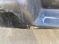 Close-up of the lower section of a 2012 GMC Savana showing visible scratches and wear on the black plastic trim and underlying metal surface