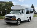 A white 2013 Chevrolet Express vehicle designed for transportation with large windows and accessible features