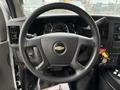 Steering wheel of a 2020 Chevrolet Express featuring the Chevrolet logo and control buttons with an instrument panel and gear shift visible in the background