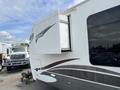 A 2013 Outdoor Wind River with a side slide-out mechanism extended showcasing its curved design and gray accents