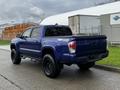 A blue 2022 Toyota Tacoma with a truck bed and black wheels parked on a paved surface