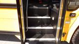 Stairs leading up into a 2014 Freightliner Thomas Diesel school bus with black textured steps and yellow exterior