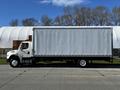 A white 2016 Freightliner M2 106 box truck with a large blank cargo area on the side is parked on a roadway