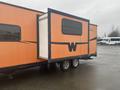 2015 Winnebago Of Indiana Travel Trailer with an orange exterior and a black stripe featuring a large retractable slide-out section on the side