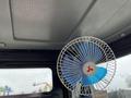 A small blue and white portable fan mounted inside the cabin of a 2024 AGT Industrial Yellow H13R Mini Excavator