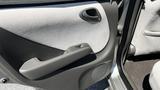 Interior of a 2006 Honda Fit showing the driver's side door panel with a gray fabric surface and a door handle