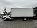 A 2018 Freightliner M2 106 box truck with a white cargo area and black cab parked on a concrete surface