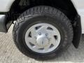 A close-up of a silver wheel with a Ford logo and rugged black tire on a 2004 Ford Econoline vehicle
