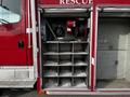 Close-up of a red 1994 Freightliner FL80 rescue truck with open compartments displaying stacked shelves and equipment storage