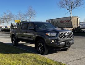 A gray 2021 Toyota Tacoma pickup truck is parked with its front facing the viewer showcasing its bold grille and rugged design