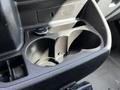 A close-up view of the cup holder area in a 2015 Ford Transit featuring two cup holders and a power outlet