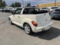A white 2005 Chrysler PT Cruiser convertible with a black soft top parked on a gravel surface