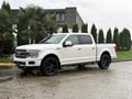 A white 2018 Ford F-150 with black rims parked on a wet surface
