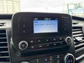 The dashboard of a 2023 Ford Transit displaying a radio screen with song information and control buttons