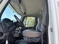 Interior of a 2015 Freightliner M2 106 showing the driver's seat steering wheel dashboard and control panel with gray fabric upholstery