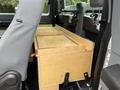A wooden storage box is positioned between the front seats of a 2015 Ford F-350 SD with gray fabric upholstery