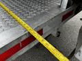 A 2011 Ford F-550 truck with a silver metal bed and a measuring tape laid across the edge of the truck bed showing measurements