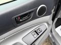 Interior door panel of a 2015 Toyota Tacoma featuring a door handle power window controls and a speaker with textured surfaces
