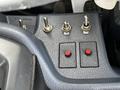Close-up of control panel featuring multiple toggle switches and two red buttons in a 2006 Hino 268 vehicle