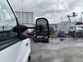 A 2017 Ford Econoline van with a side mirror prominently visible in the foreground showing a reflection of the surroundings