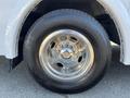 A close-up of a polished chrome wheel from a 2016 Chevrolet Express showing multiple bolts and a large black tire with a tread pattern