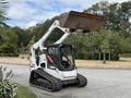 A 2017 Bobcat T740 skid-steer loader with a raised bucket and rubber tracks positioned on a paved surface
