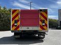 A red and white 2009 Ford F-550 with a flatbed design featuring reflective striped markings on the rear end