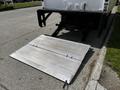 A silver loading ramp connected to the rear of a 2016 Isuzu NQR truck