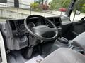 Interior of a 2018 Isuzu NPR showing the steering wheel dashboard gear shift and driver's seat with control buttons