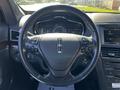 The image shows the steering wheel of a 2013 Lincoln MKT featuring control buttons and a dashboard display in the background
