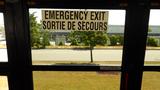 A sign on the inner door of a bus indicating the emergency exit in English and French