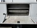 A 2008 Ford F-550 with an open storage compartment displaying metal shelving and a weathered floor