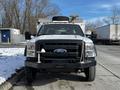 A white 2011 Ford F-450 SD with a black grille and several orange lights on the roof is parked facing forward