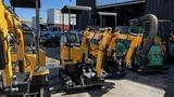 A yellow 2021 Cael-1T Mini excavator with dual arms and a bucket attachment is positioned in the foreground with other machinery visible behind it