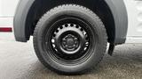 A close-up of a black steel wheel with a five-bolt pattern mounted on a 2012 Ford Transit tire