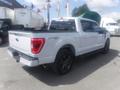 A white 2022 Ford F-150 with a black bed cover and dark alloy wheels viewed from the rear angle