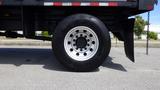 A close-up of a black tire with silver rim from a 2012 International DuraStar 4300 showing multiple round holes in the rim and tread design on the tire