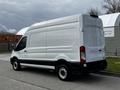 A white 2020 Ford Transit van with a high roof and cargo area, featuring black accents on the lower part and standard wheels