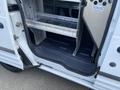 A 2013 Ford Transit Connect with an open side door revealing an empty interior and metal shelving unit